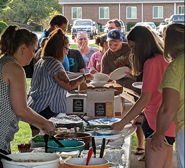 A group of people getting food at a potluck